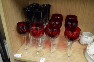 Two sets of ruby colour drinking glasses.