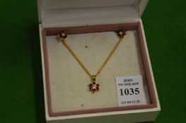 A gold diamond and ruby flower head pendant with chain together with a pair of matching earrings.