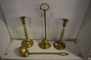 A brass door stop, pair of brass candlesticks and a ladle.