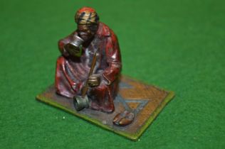A small cold painted bronze model of an Arab on a carpet.