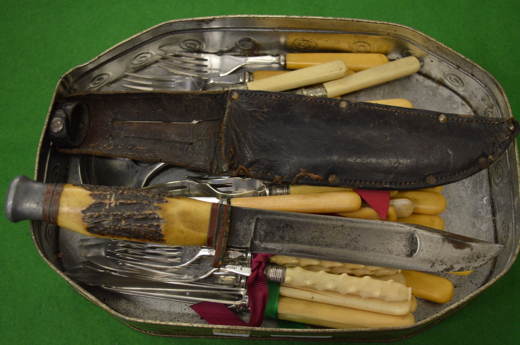 A sheath knife with antler handle and a quantity of flatware.