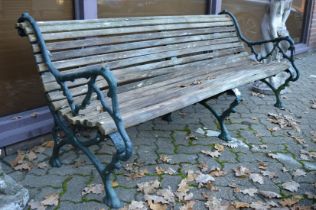 A large garden bench with wooden slats and cast iron supports.