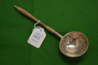 A white metal straining spoon.