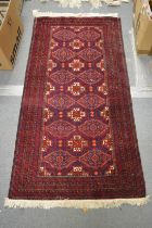 A Persian rug, dark red ground with stylised decoration 155cm x 80cm.