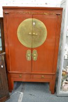 A Chinese red lacquer and brass mounted wardrobe.