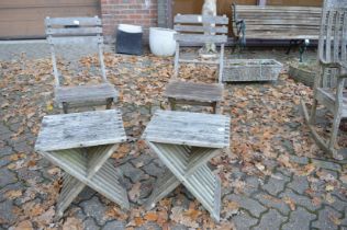 A pair of folding chairs with a pair of occasional tables.