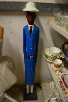 A carved and painted wood standing figure of a policeman.