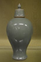 A Chinese celadon glazed baluster shaped vase and cover.