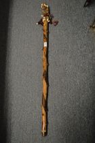 An African staff with decorative shell and woven cloth grip handle.