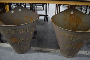 A pair of large metal grape harvesting buckets.