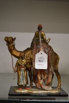 A Burgman style painted metal table lighter modelled as Arabian carpet sellers seated on a camel.