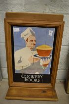 A tile plaque advertising cookery books, framed.
