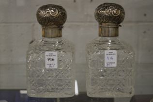 A pair of large cut glass scent bottles with embossed silver covers.