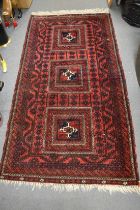 A Persian rug, red ground with three large central motifs 195cm x 105cm.