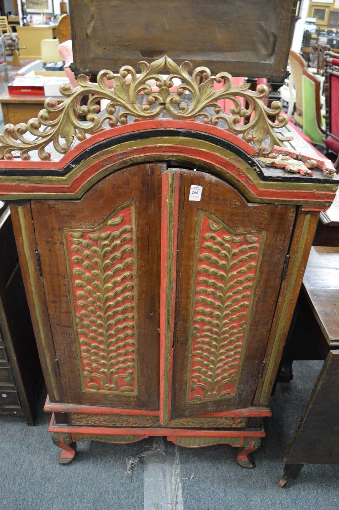 An Eastern carved hardwood painted and gilded low two door cupboard.