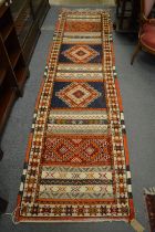 An Afghan runner with bands of stylised decoration 300cm x 80cm.