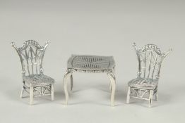 A miniature silver table and two chairs.
