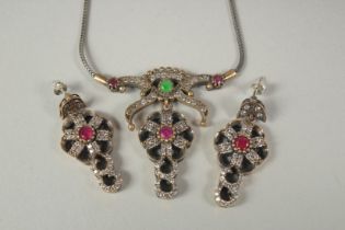 A silver ruby and emerald necklace and earrings in a box.