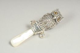 A silver and mother of pearl owl rattle.