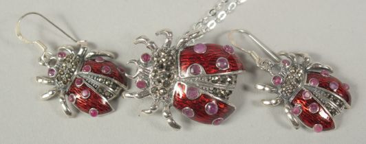 A silver and ruby set ladybird pendant chain and earrings in a box.