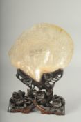 A CHINESE CARVED MOTHER OF PEARL SHELL, on a carved and pierced hardwood stand.