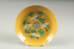 A FINE CHINESE IMPERIAL YELLOW GROUND PORCELAIN DISH, depicting four cranes amongst clouds with