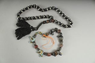 A SET OF SILVER INLAID PRAYER BEADS, together with a string of antique Islamic glass beads, (2).