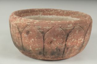 A FINE 17TH CENTURY MUGHAL INDIAN CARVED RED STONE BOWL, the exterior carved with lotus petals, 28cm