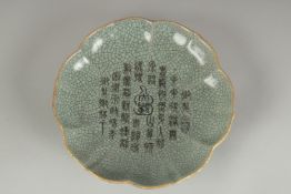 A CHINESE CELADON CRACKLE GLAZE PETAL-RIM DISH, the centre with incised characters, 19cm wide.