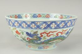 A CHINESE WUCAI PORCELAIN BOWL, painted with dragons and flora, 20.5cm diameter.