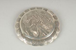 A CHINESE SILVER CIRCULAR COMPACT with a figure on a pathway beside a building. 3.5Iins diameter.