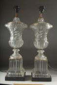 A GOOD PAIR OF GLASS URN SHAPED LAMPS on square pedestals. 22ins high.