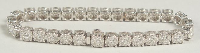 A SUPERB 18 CARAT WHITE GOLD ILLUSION SET DIAMOND LINE BRACELET with 30 cluster set diamonds. 20cm