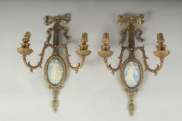 A PAIR OF GILT METAL TWO LIGHT WALL SCONCES with oval Wedgwood Jasper plaques. 14ins long.