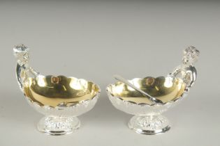 A PAIR OF SILVER PLATED CHERUB SALTS AND SPOONS.