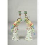 A PAIR OF GREEN PORCELAIN PARAKEET CANDLESTICKS on encrusted tree stumps. 13ins high.