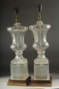 A GOOD PAIR OF GLASS URN SHAPED LAMPS on square pedestals. 22ins high.