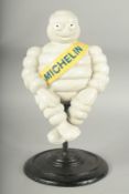 A PAINTED CAST IRON MICHELIN MAN ON A STOOL, 16ins high.