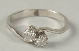 A PLATINUM AND DIAMOND TWO STONE CROSS OVER RING Ring size K.