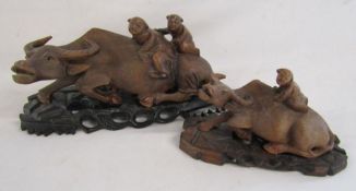 Pair of carved wood water buffalo with figures on their back with stands largest approx. 29cm