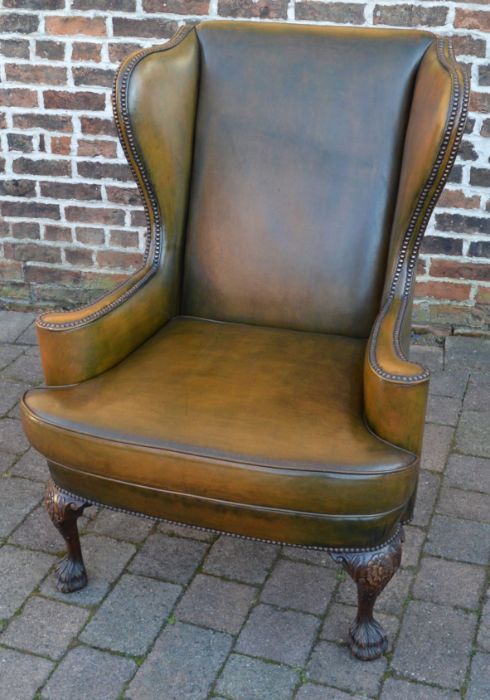 Leather wing back armchair with ornately carved front legs on hairy paw feet