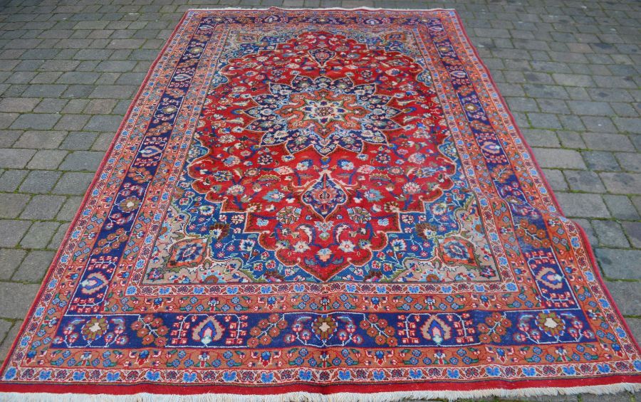 Red ground Persian Mashad carpet with floral medallion 302cm by 195cm