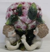 Continental porcelain jardiniere supported by cherubs with raised flowers & foliage & underglaze
