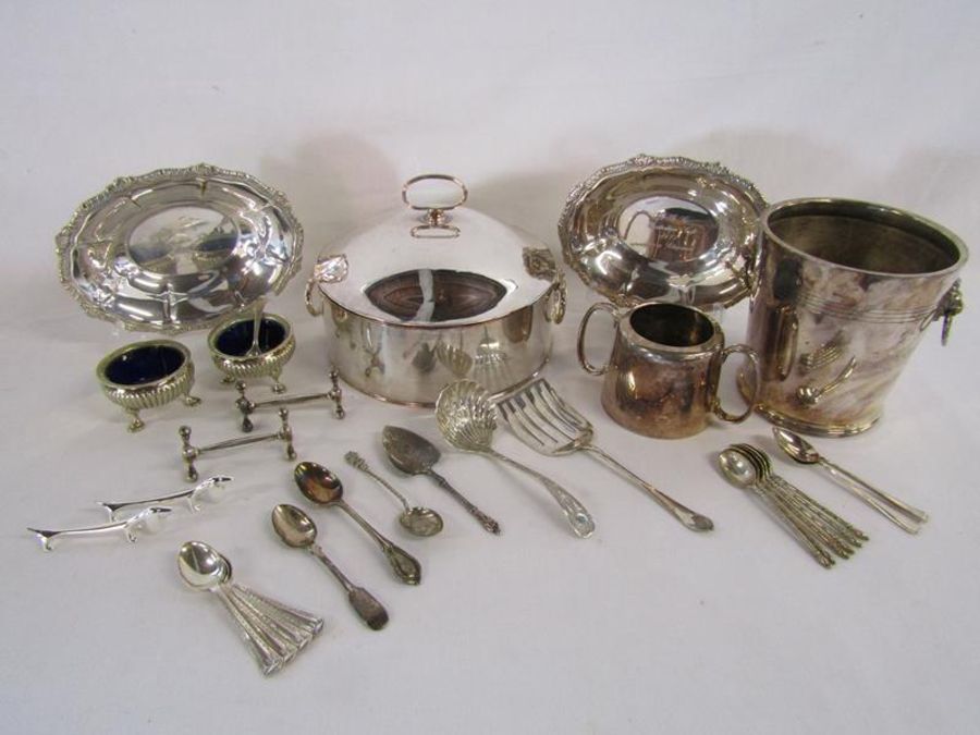 Collection of silver plate to include muffin warmer, ice bucket, carving rests, spoons etc