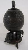 Ebonised carved coconut shell on 3 elephant backs with elephant handled lid - approx. 25cm tall