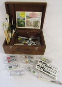Box containing Bob Ross paints and accessories, paint brushes and painting books