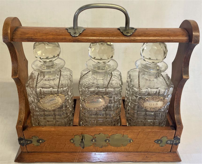 Oak tantalus with decanters bearing Birmingham W I Broadway & Co silver labels