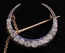 Antique diamond set crescent brooch in platinum, with safety chain, approximately 1ct diamond total,