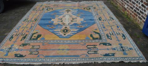 Large red ground wool carpet with blue central medallion, 365cm x 300cm