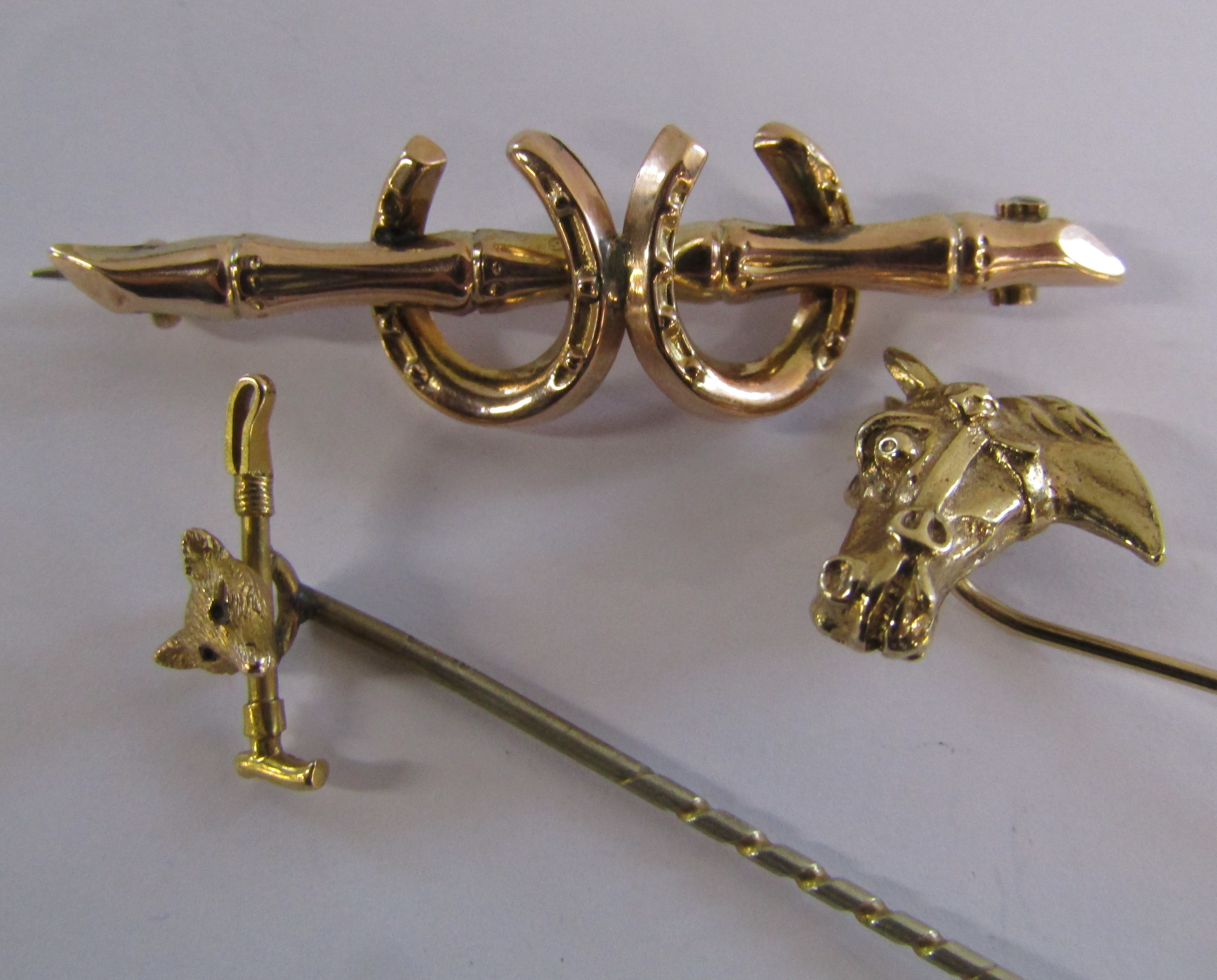 9ct gold horseshoe brooch, 9ct gold horsehead tie-pin and 9ct gold fox head and whip with gilt pin